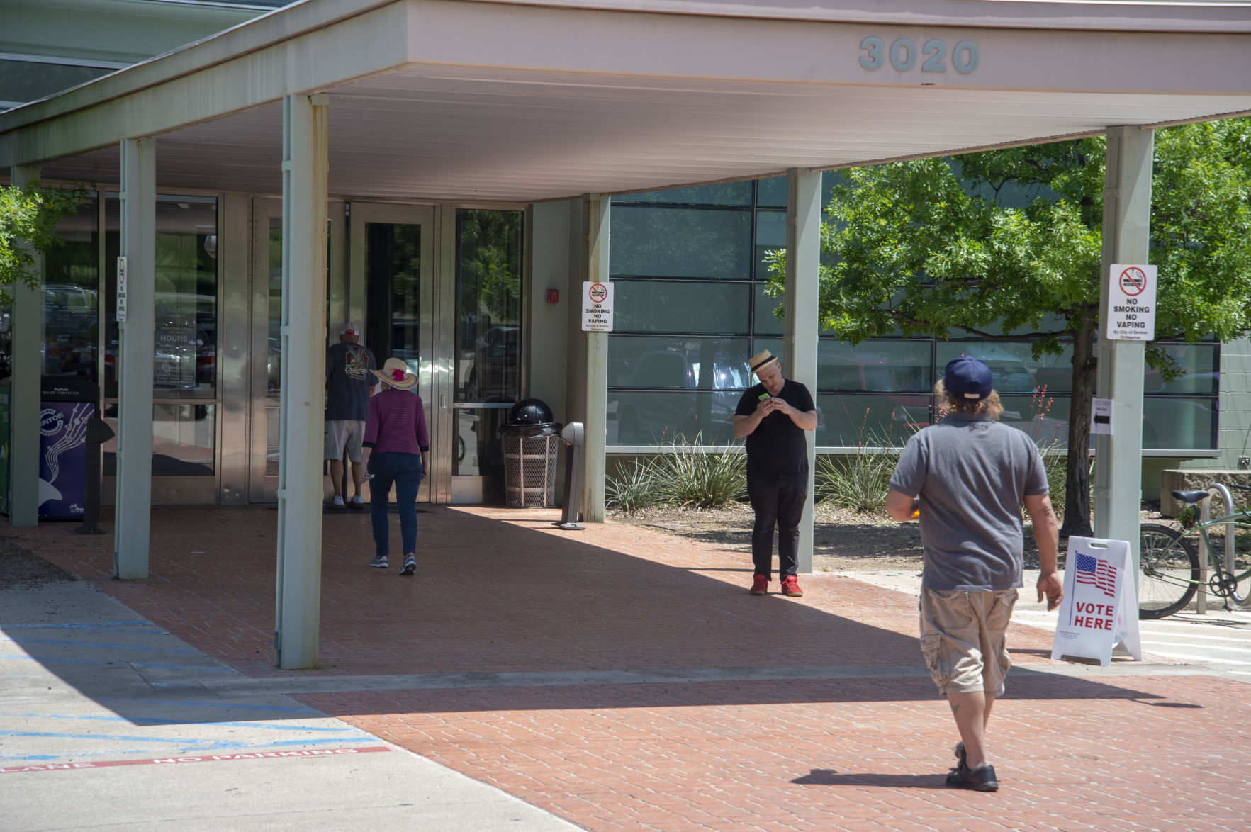 Denton residents walk in and out of the Denton Public Library North Branch this afternoon on voting day. The library served as a polling location for the local precinct.